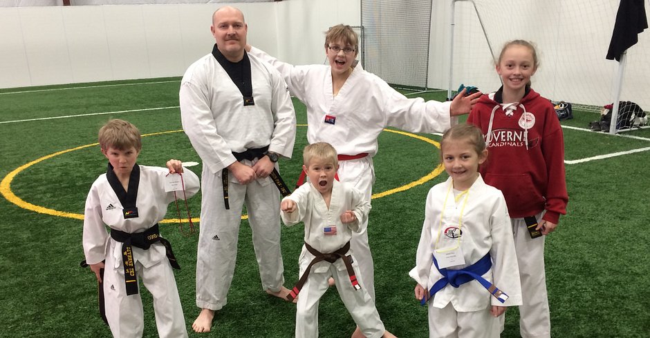 Adults and Kids showing off their Tae Kwon Do uniforms some happy some with their game face